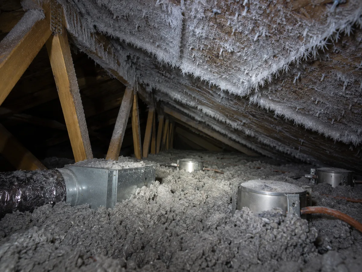 Frost on the roof deck above a bath fan and can lights in the attic of a newer Shakopee home